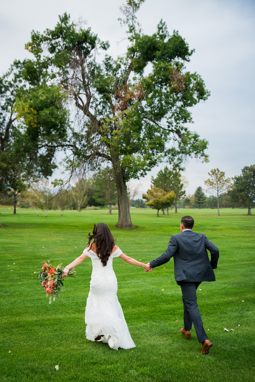 A bride and groom running through the golf course at The Barn at Raccoon Creek.