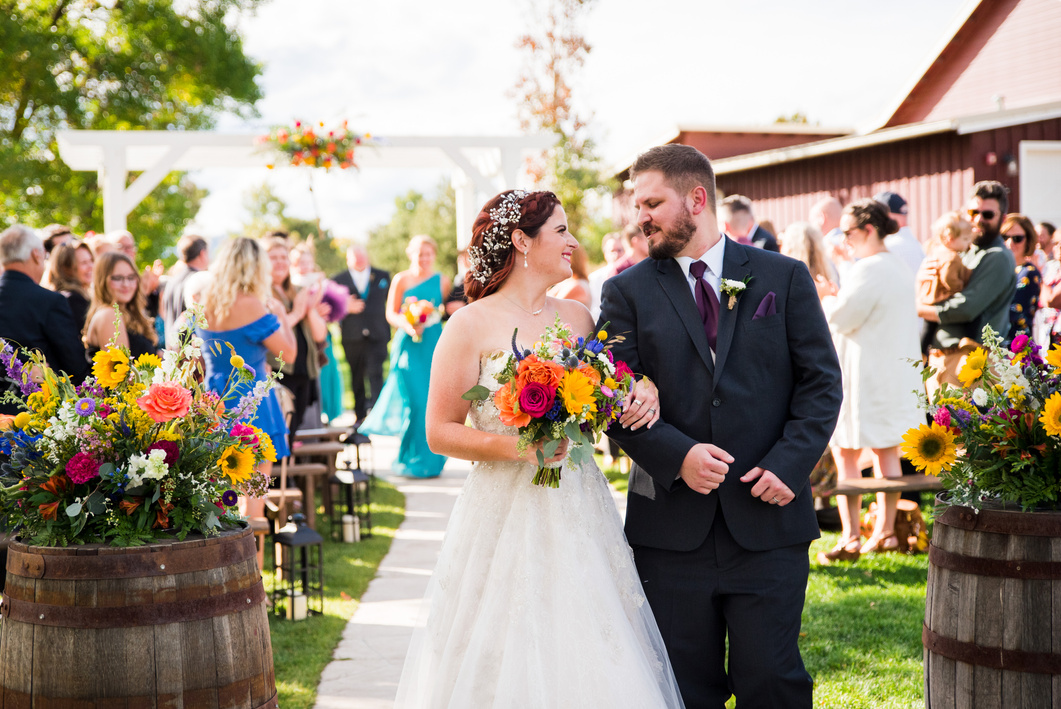 A bride and groom walk up the aisle during a wedding ceremony at the Barn at Raccoon Creek in Littleton, Colorado.