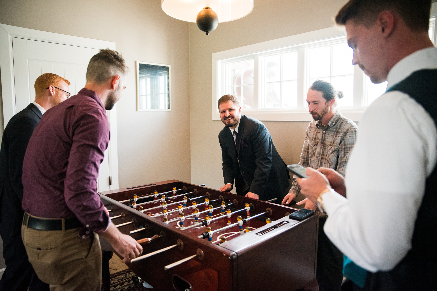 A group of groomsmen playing foosball in a room at the Barn at Raccoon Creek.