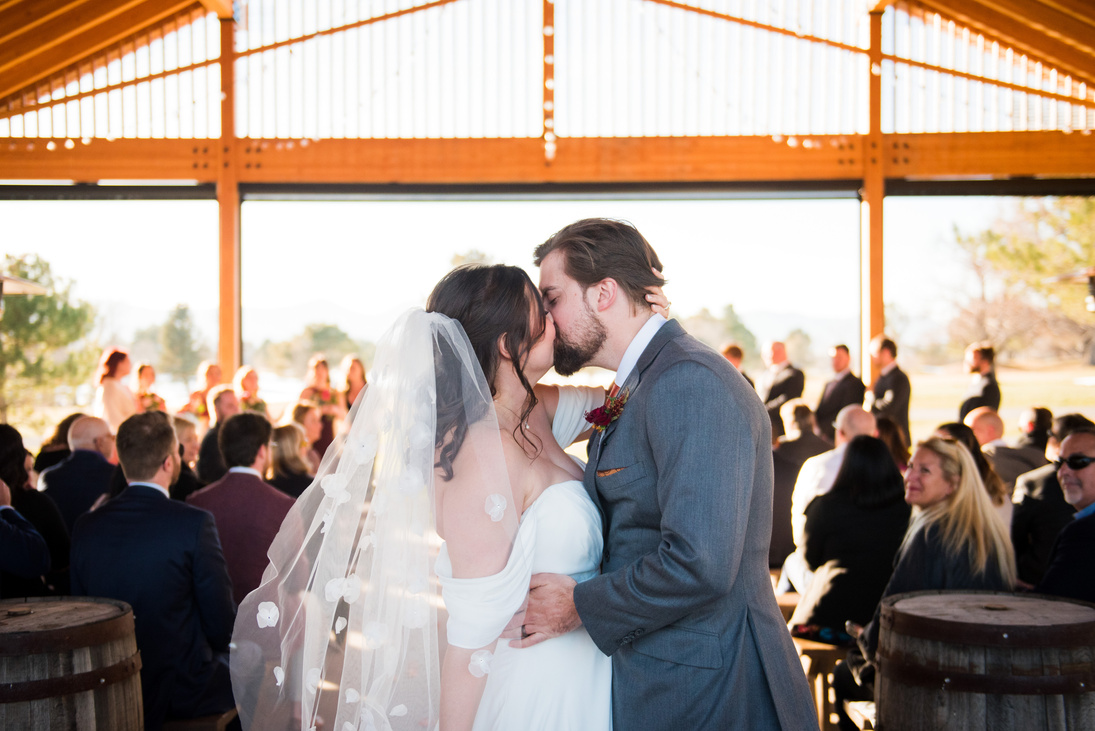 A bride and groom share a kiss at the end of the aisle after their wedding ceremony.