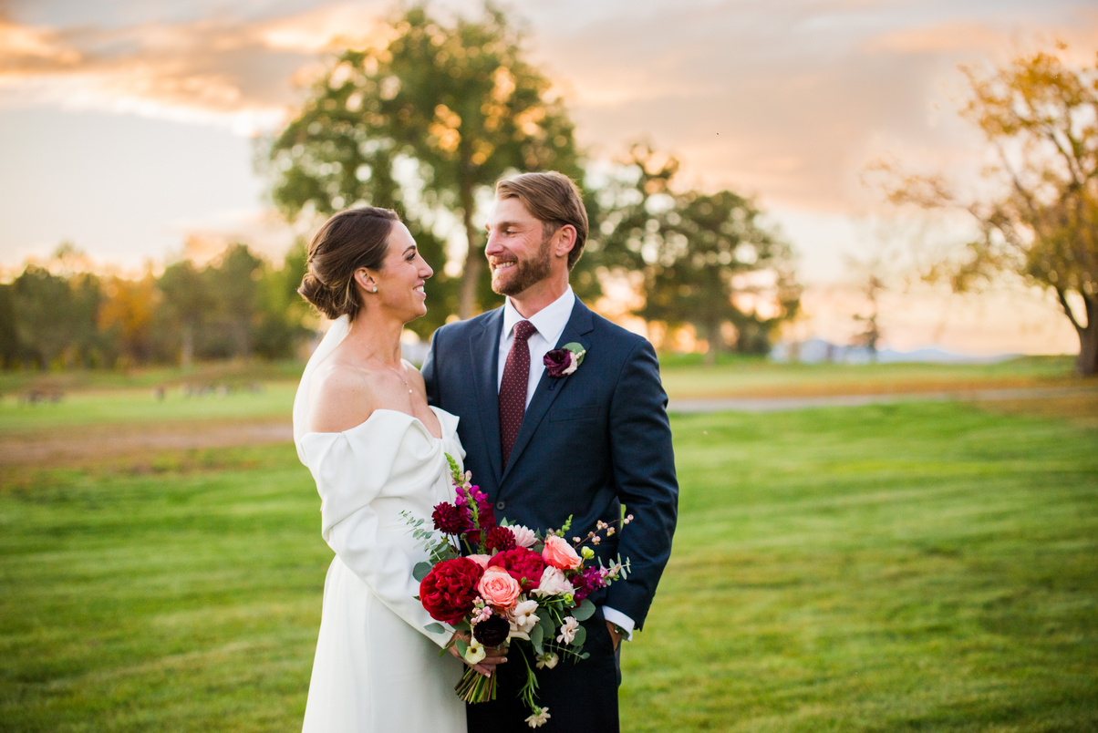 A bride and groom smile at each other during golden hour at The Barn at Raccoon Creek in Littleton, Colorado.