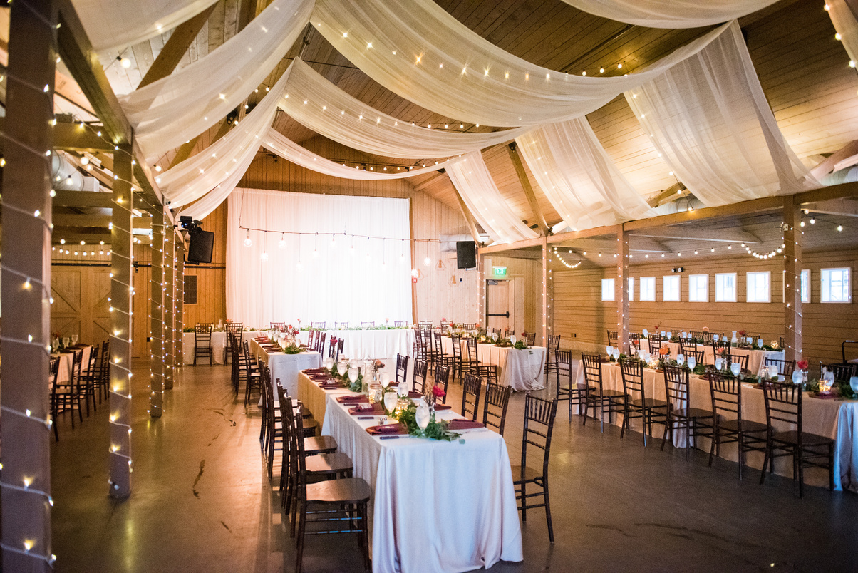 Wedding reception in a barn with white drapes and string lights at The Barn at Raccoon Creek.