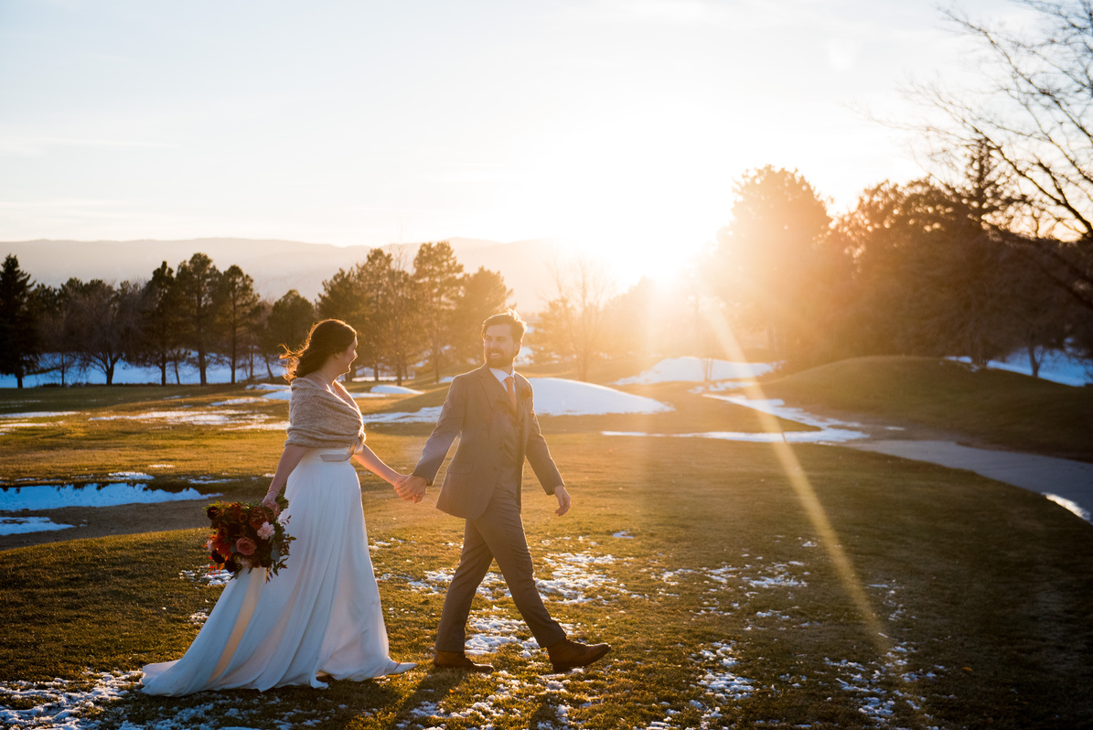A bride and groom walk across the golf course at sunset at The Barn at Raccoon Creek.